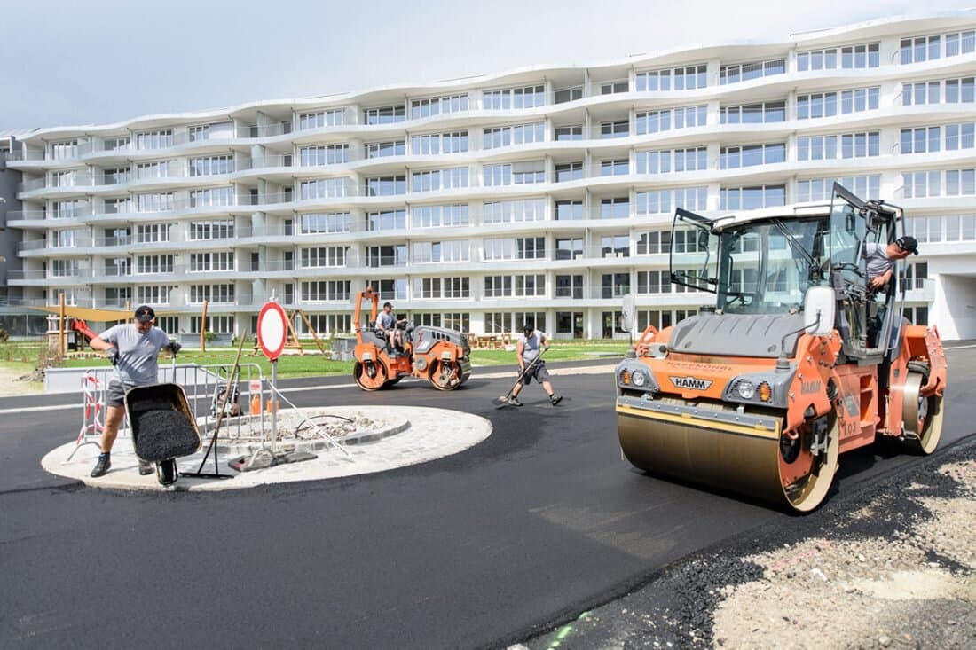 Walze auf neuem Asphalt vor Wohnbau