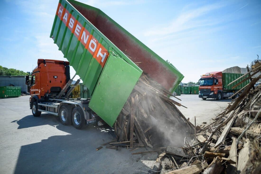 Grüne Mulde kippt Schutt ab